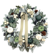 Decorative wreath with greenery, pumpkins, and ribbons on a white background