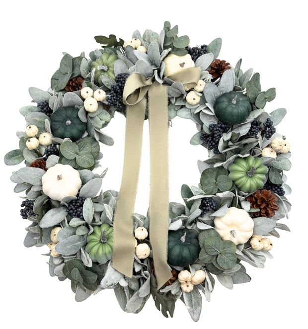 Decorative wreath with greenery, pumpkins, and ribbons on a white background